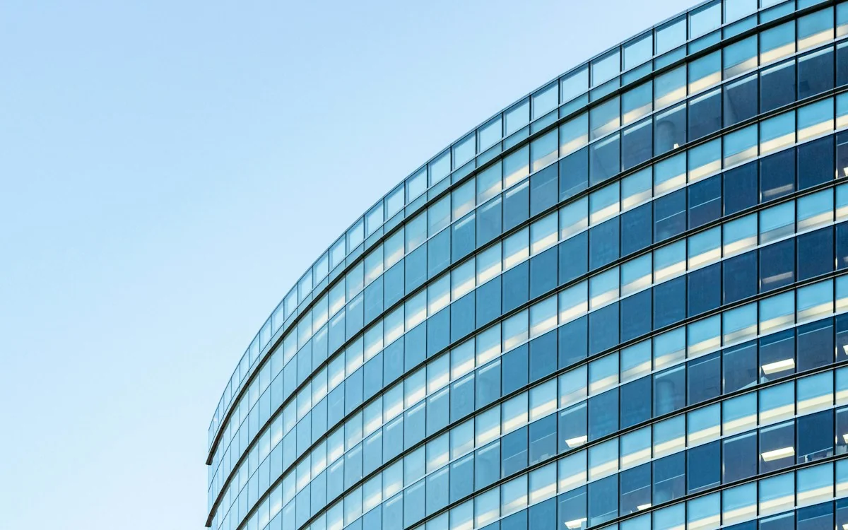 Modern office architecture with a curved glass facade against a blue sky